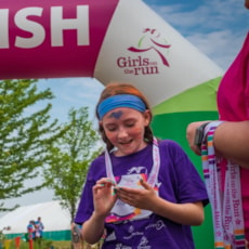 Girls on the Run participant smiles and looks at a medal